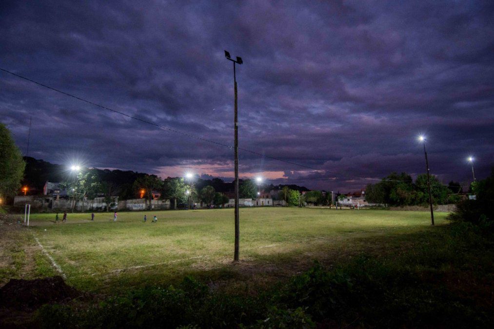 Niños jugando en el predio deportivo con sus reflectores funcionando 